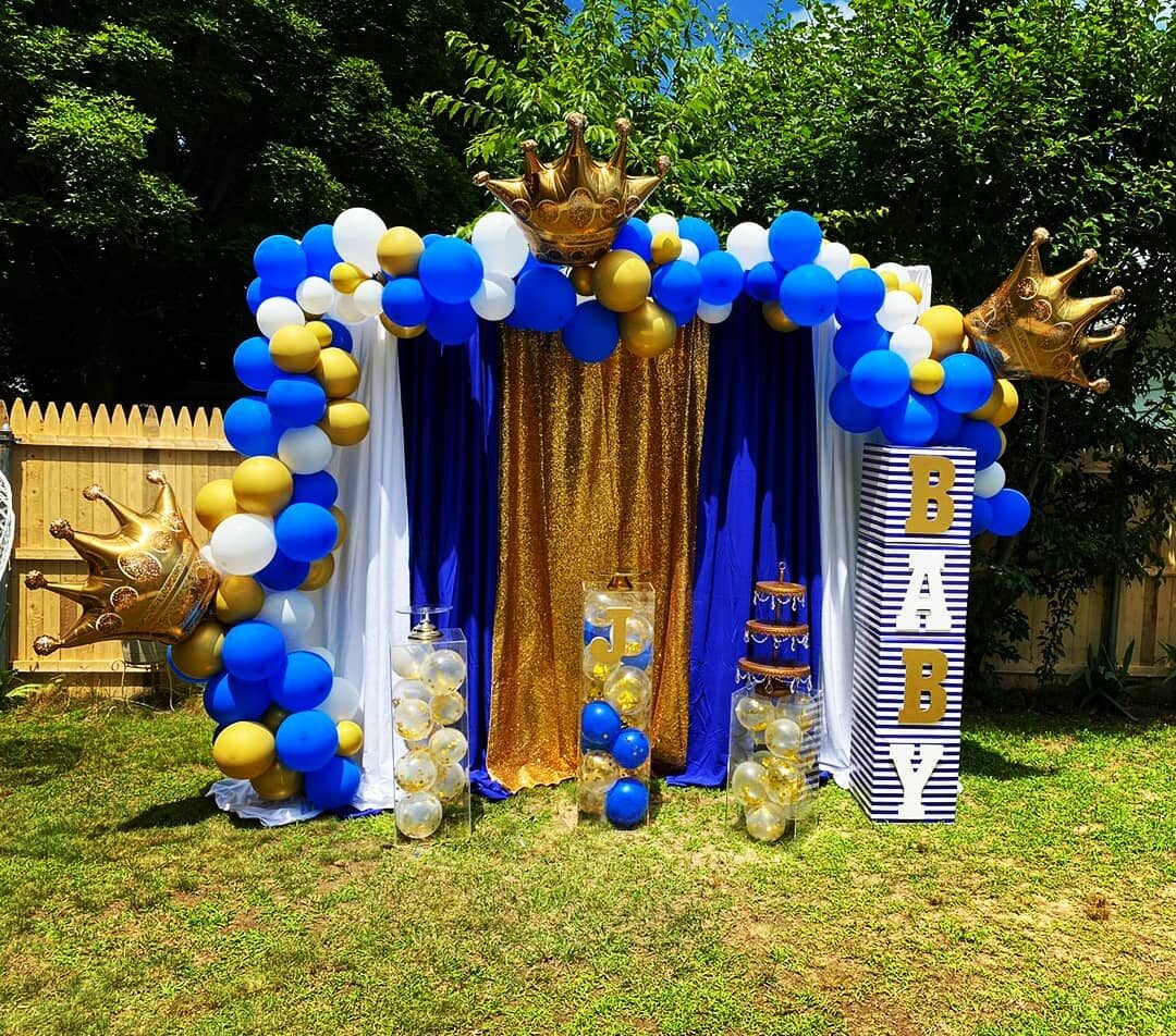 Royal blue and gold crown-themed balloon arch at a baby shower