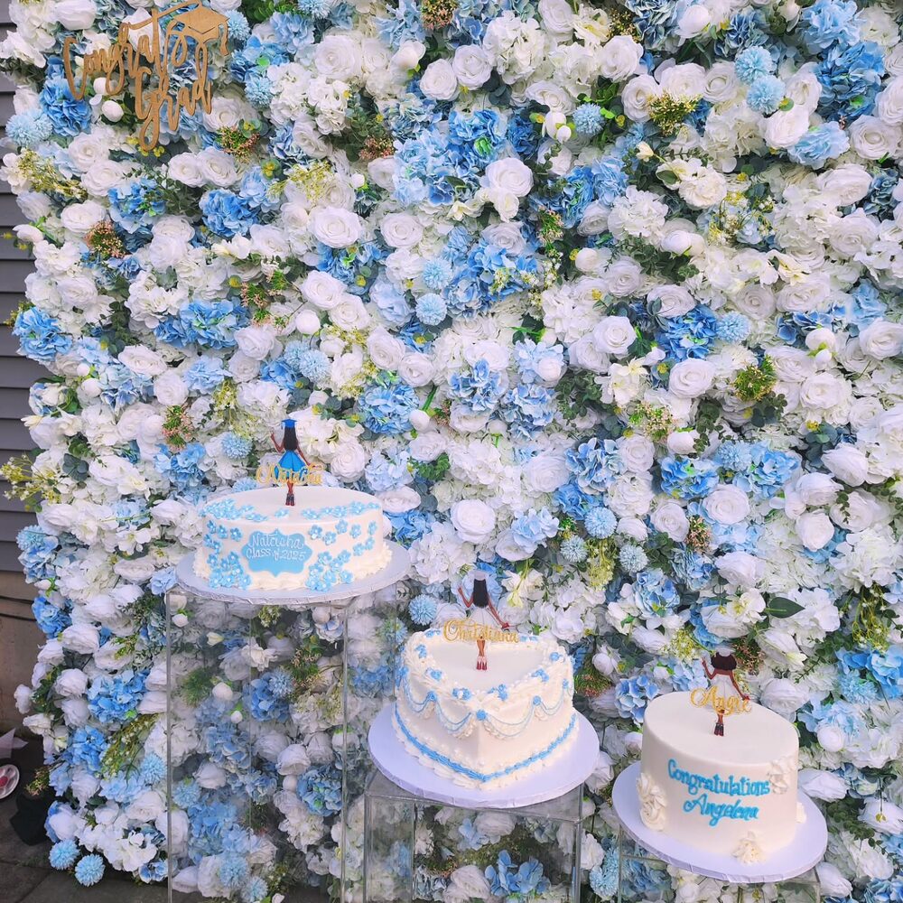 Blue and white flower wall with cakes at a graduation party