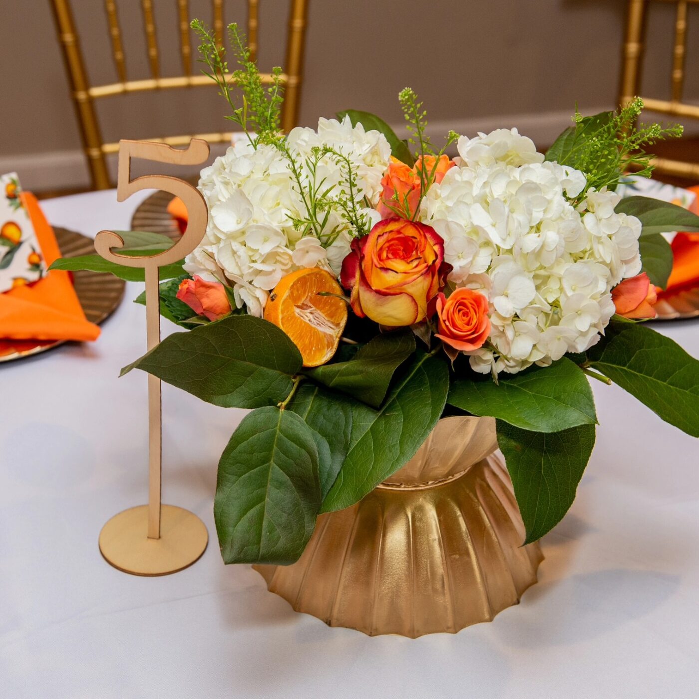 Orange and white citrus centerpiece with gold table number
