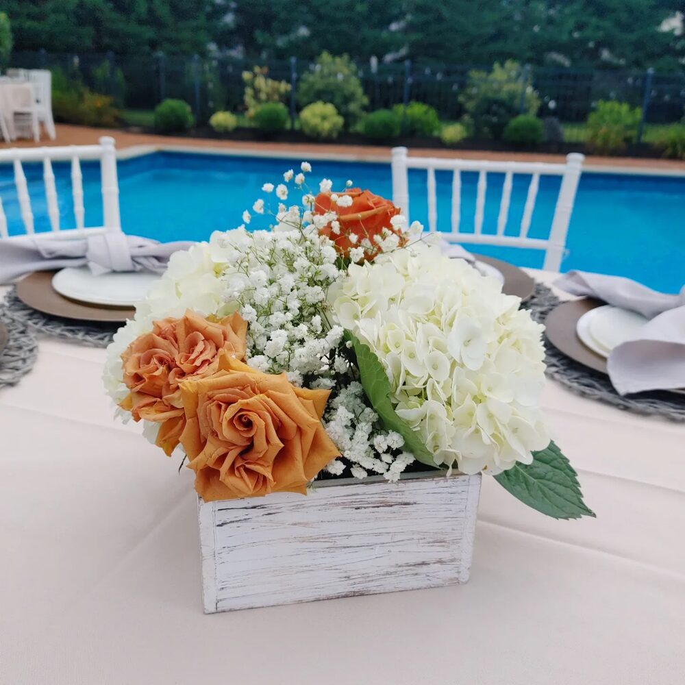 Orange and white rose and hydrangea centerpiece at a poolside event