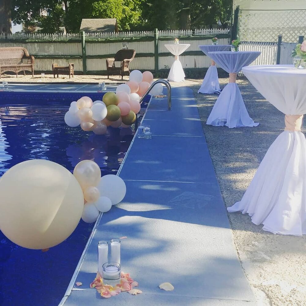 Poolside cocktail tables with blush and white balloons