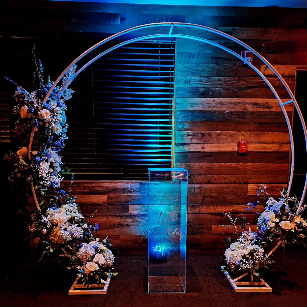 Blue neon circle arch with florals at a Sweet 16 party