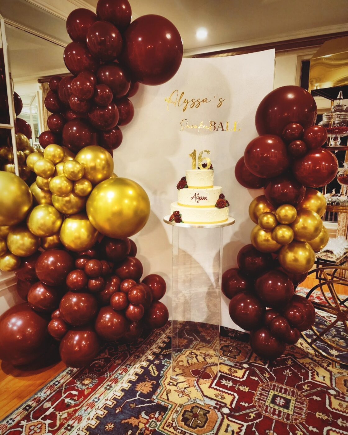 Burgundy and gold balloon arch with cake, Sweet 16 celebration