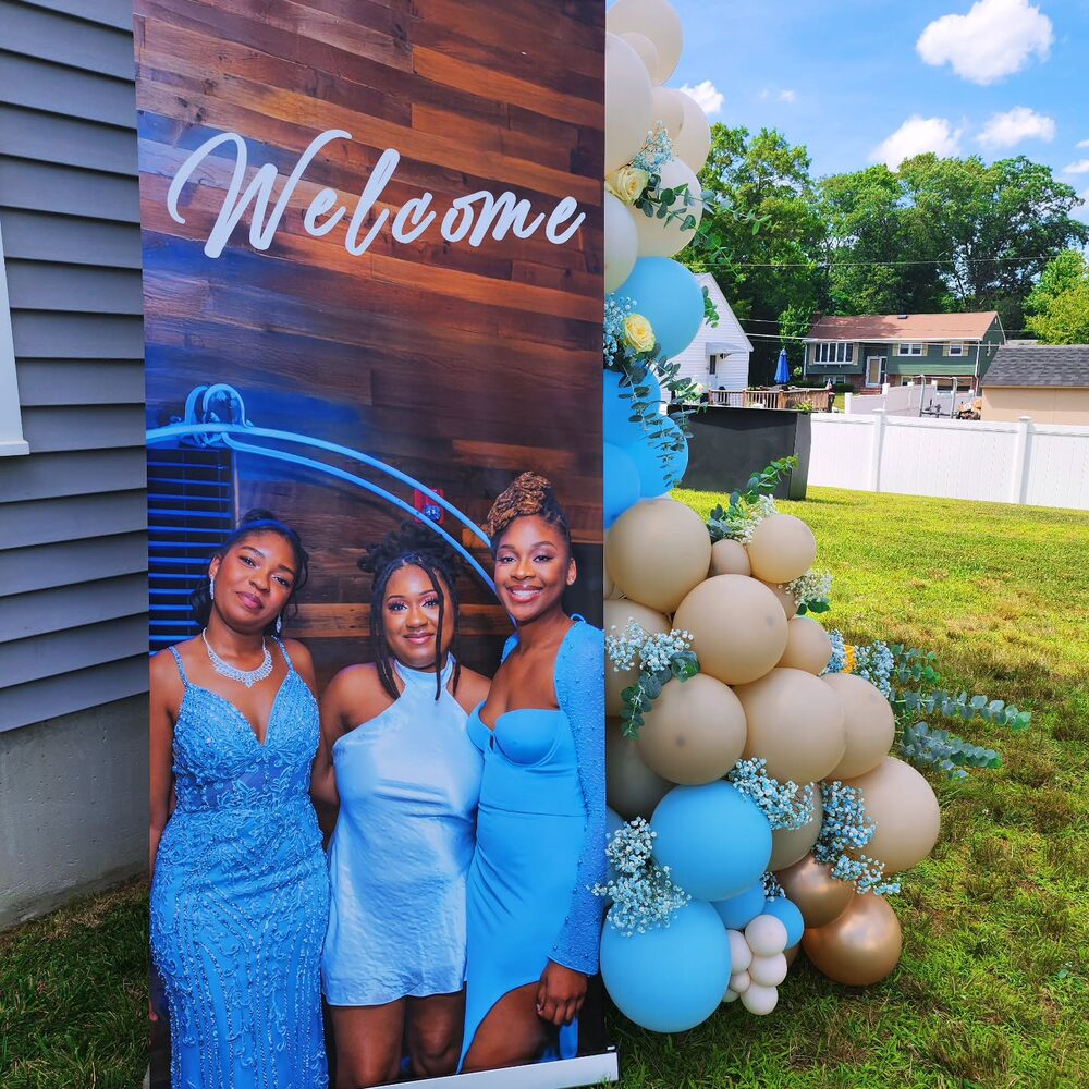 Welcome sign with blue dresses and cream balloon arch